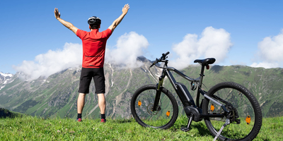 Diese Leistungen bietet dir in Amprio RMAG Motor Person steht neben einem E-Bike auf einer grünen Wiese