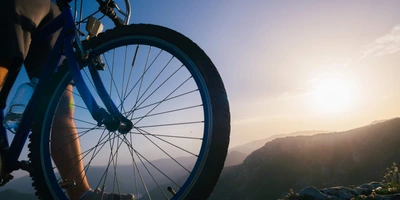 Berg- und Talfahrt - sicher auf die Berge Ein Fahrrad im Morgengrauen zwischen Bergen