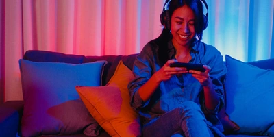 Frau sitzt auf einem Sofa und spielt auf Smartphone