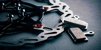 So kannst du die Bremsbeläge am Fahrrad wechseln Bremsbeläge und Bremsscheibe auf einem dunklen Untergrund