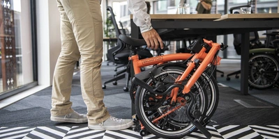 Das Brompton Faltrad kann aufgrund seiner Faltbarkeit super ins Büro mitgenommen werden Faltrad im Büro
