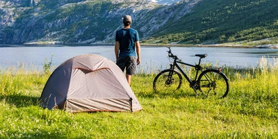 Urlaub mit dem Rad Mann macht Urlaub mit Zelt und Fahrrad am Seeufer in der Natur