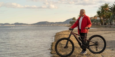 Mann steht mit Mountainnbike am Strand