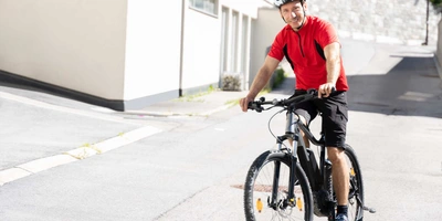 Mann mit Helm fährt Fahrrad auf der Straße.