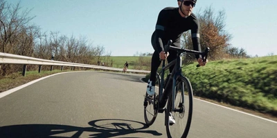 Mann fährt auf Rennrad über Strasse.