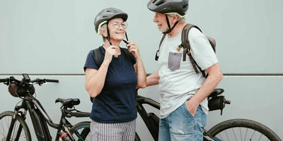 Zwei ältere Menschen stehen von Fahrrädern und lächeln.