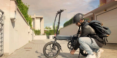 Mann mit Helm setzt Akku an faltbarem E-Bike ein.