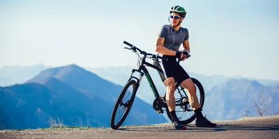 Mann auf Crossbike steht in der Landschaft