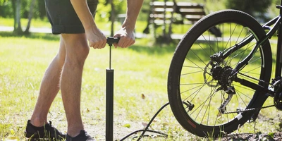 Eine Person pumpt den Reifen eines Fahrrads auf.
