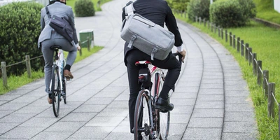 Zwei Männder in Businesskleidung fahren mit dem Fahrrad. 