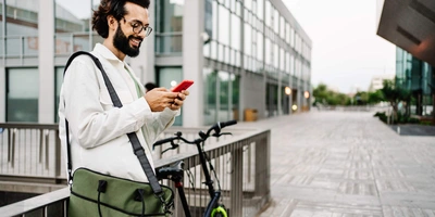 Mann steht neben Rad mit Handy in der Hand