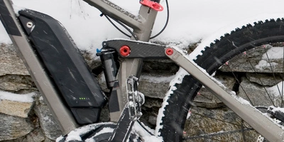 E-Bike Akku Winter: Nutzung, Ladung, Lagerung & Co. Ein E-Bike mit Schnee und Steinmauer im Hintergrund, Fokus auf dem Antriebssystem.