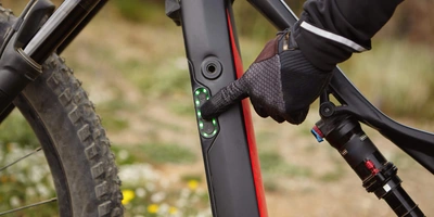Eine Person in Handschuhen drückt einen Knopf an einem E-Bike-Rahmen