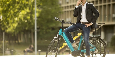 E-Bike statt Auto Mann sitzt auf einem stehenden Fahrrad und telefoniert