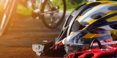 Ein Fahrradhelm, Sonnenbrille und Handschuhe liegen dem Boden, das Fahrrad ist im Hintergrund