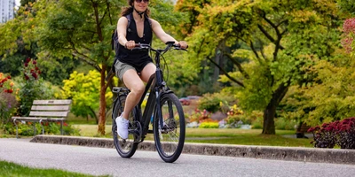 Frau auf Fahrrad fährt durch Park.