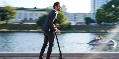 Mann im Anzug fährt auf einem E-Scooter