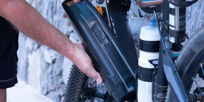 Mann tauscht Batterie seines E-Bikes