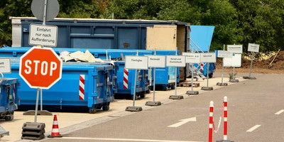 Wertstoffhof mit mehreren Containern und Stoppschild.