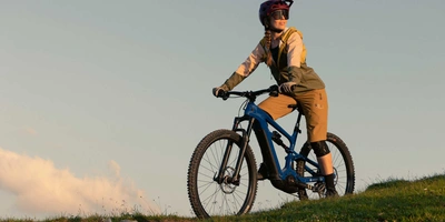 Mit Bosch Motoren werden jedes Jahr über 3 Millionen Kilometer alleine in Deutschland zurückgelegt. Frau mit Helm auf Mountainbike fährt Berg hinunter.