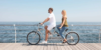 Mann und Frau sitzen auf Tandem E-Bike.