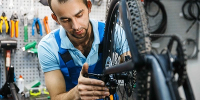 Diese E-Automatikschaltungen sind die Besten. Mann führt Reparaturen an Fahrrad-Schaltung durch.