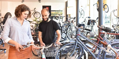 Mann und Frauen stehen vor einem Fahrrad und begutachten es.