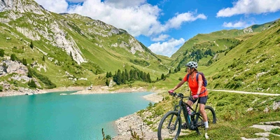 Darauf kommt es beim Crossbike-Kauf an. Frau steht auf Crossbike neben See zwischen Bergen.