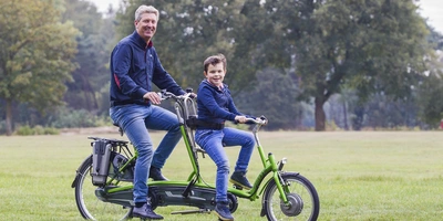 Ein Mann und ein Kind sitzen auf einem Tandem.
