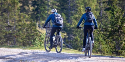 Gute & Günstige E-Mountainbikes? So geht's. Zwei Frauen fahren auf E-Mountainbike durch die Berge.