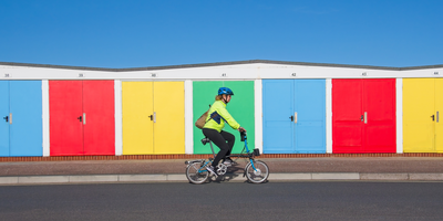 Fahrradfahrerin auf eine Faltrad fährt vor bunten Garagen