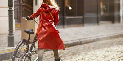 Frau in Regenjacke schiebt Fahrrad