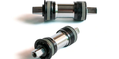 Vierkant-Lager Zwei Fahrrad-Tretlager in metallischem Finish auf weißem Hintergrund.