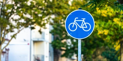 Fahrrad Verkehrszeichen: Die wichtigsten Schilder und Regeln im Überblick Blaues Verkehrsschild mit Fahrradsymbol vor grünen Bäumen.
