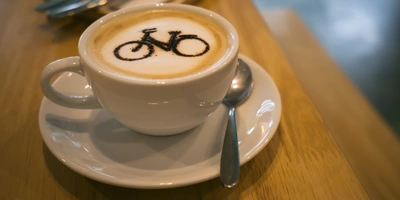 Eine Tasse Kaffee mit Milchschaum, auf dem ein Fahrrad als Latte Art zu sehen ist