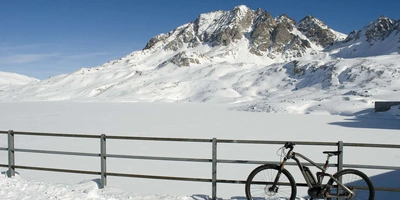 Fahrradelektronik und Akkus im Winter Fahrrad lehnt an inem Zaun vor wuinterlicher Bergkulisse