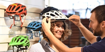Eine Frau probiert Fahrradhelme an