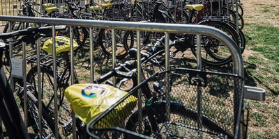 Ein Fahrradparkplatz mit vielen Fahrrädern unter blauem Himmel und Bäumen im Hintergrund.