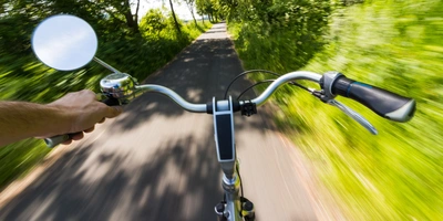 Der große Fahrradspiegel Test 2025 Radfahrer fährt mit hoher Geschwindigkeit mit einem Rad mit Fahrradspiegel