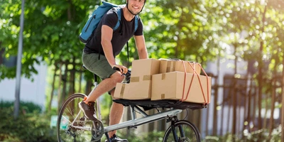 Der große Unterschied bei den Cargo Bikes Man fährt auf Cargo-Bike beladen mit Kartons