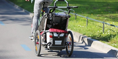 Person fährt Fahrrad mit Anhänger.