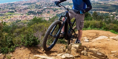 Mann fährt steilen Berg mit E-MTB hoch.