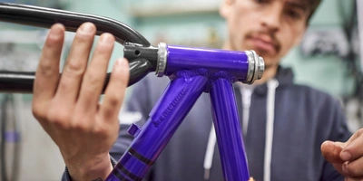 Gabelschaft kürzen - so geht's Hände montieren Teile an einem lila Fahrradrahmen in einer Werkstatt.