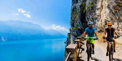 Die Szenerie am Gardasee ist einfach atemberaubend Mann und Frau fahren Radweg am Gardasee entlang