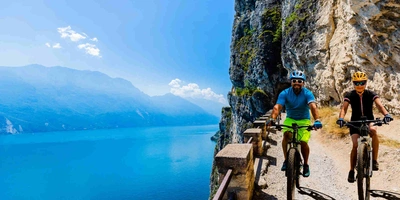 Die Szenerie am Gardasee ist einfach atemberaubend Mann und Frau fahren Radweg am Gardasee entlang