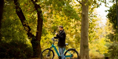 Gogobest GM29: So schlägt sich das E-Bike Schnäppchen im Test Mann steht neben E-Bike im Stadtpark