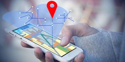 Composing aus Smartphone in der Hand eines Nutzers und grafischen Standortkoordinaten