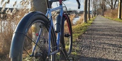Ein Gravel Bike von hinten fotografiert auf einem Schotterweg bei sonnigem Winterwetter..