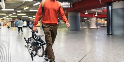 Mann trägt ein Klapprad in der U-Bahn