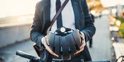 Mann steht neben Pedelec und hält seinen Helm in der Hand